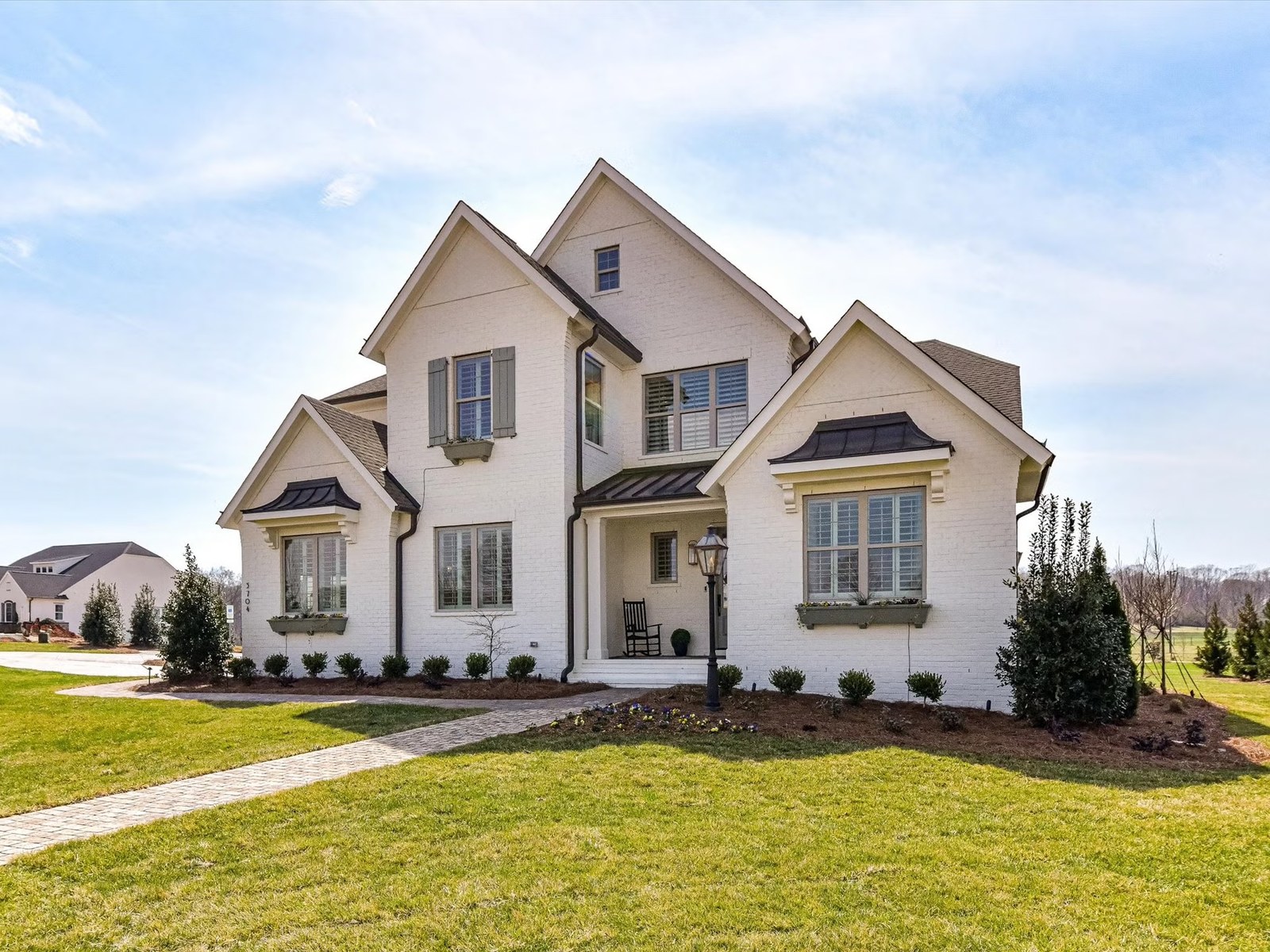 A cream stucco-and-stone two-storey home on an open lawn