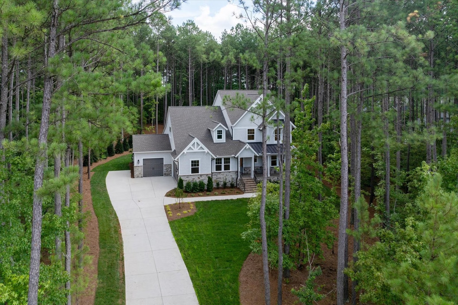 A white Carolina farmhouse set deep in pines at the end of a long drive