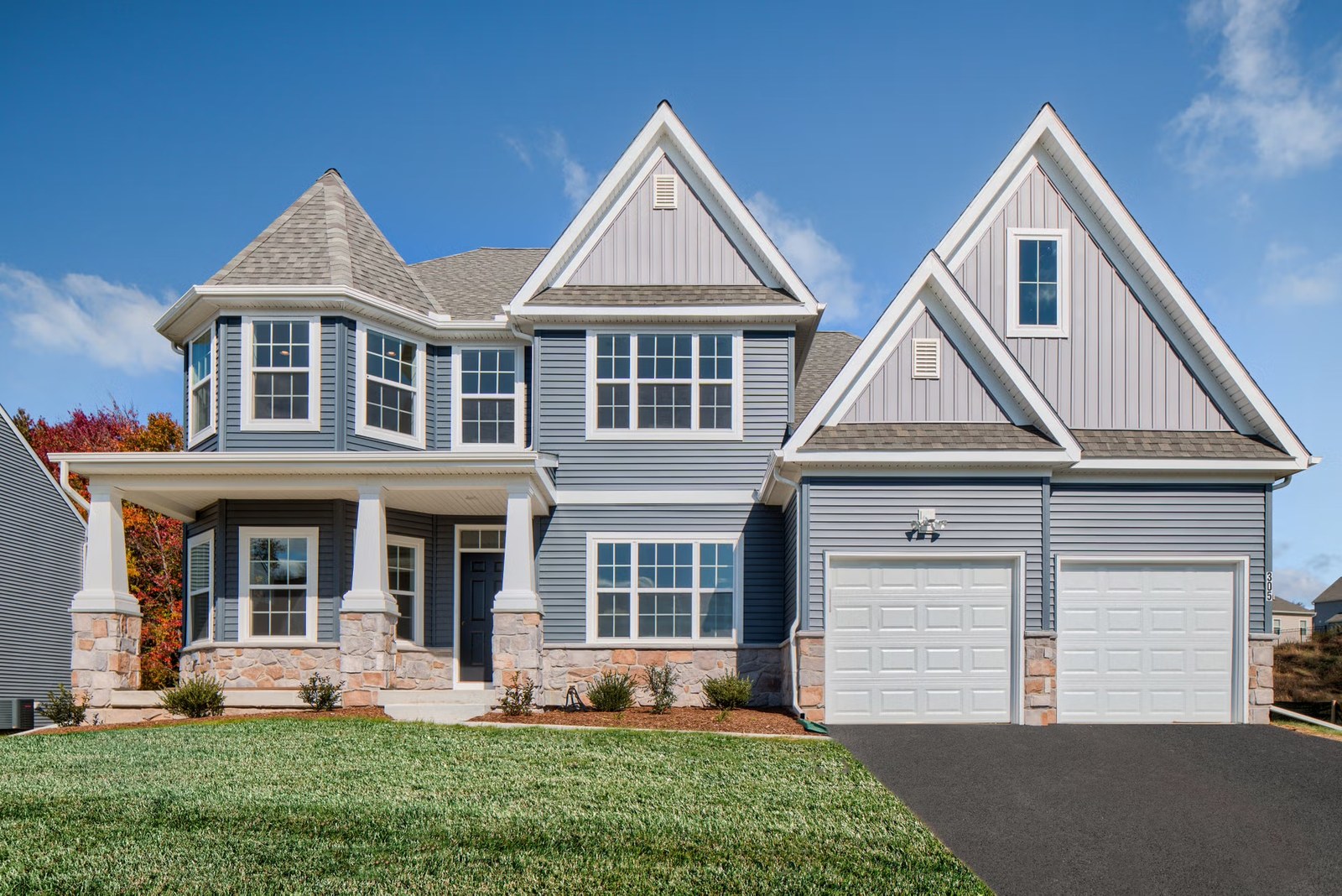 A blue-grey Carolina home with a stone base and gables
