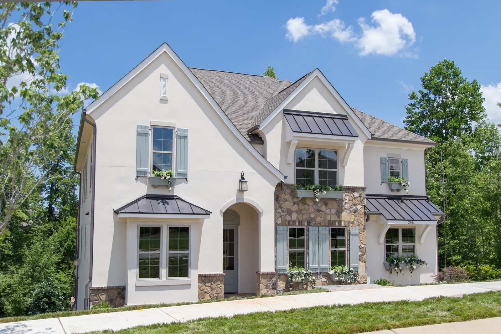 A cream stucco home with stone accents and an arched entry