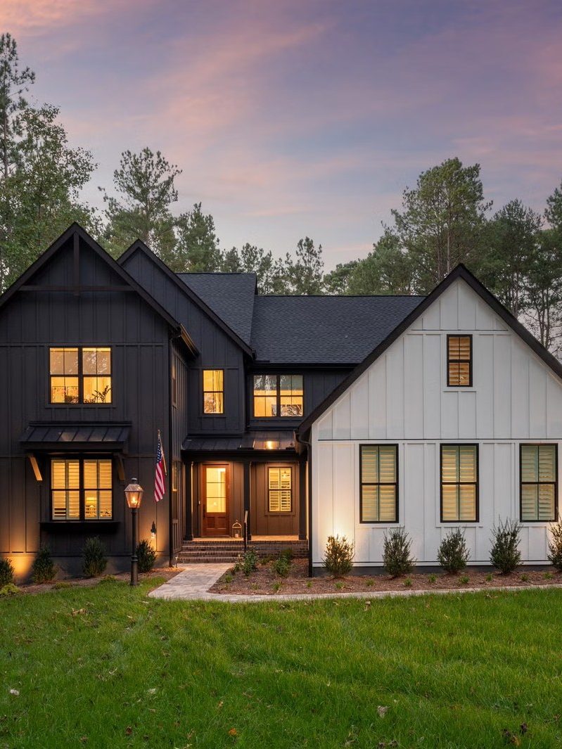 A black and white farmhouse at twilight with lit windows, illustrative of the region's newer construction