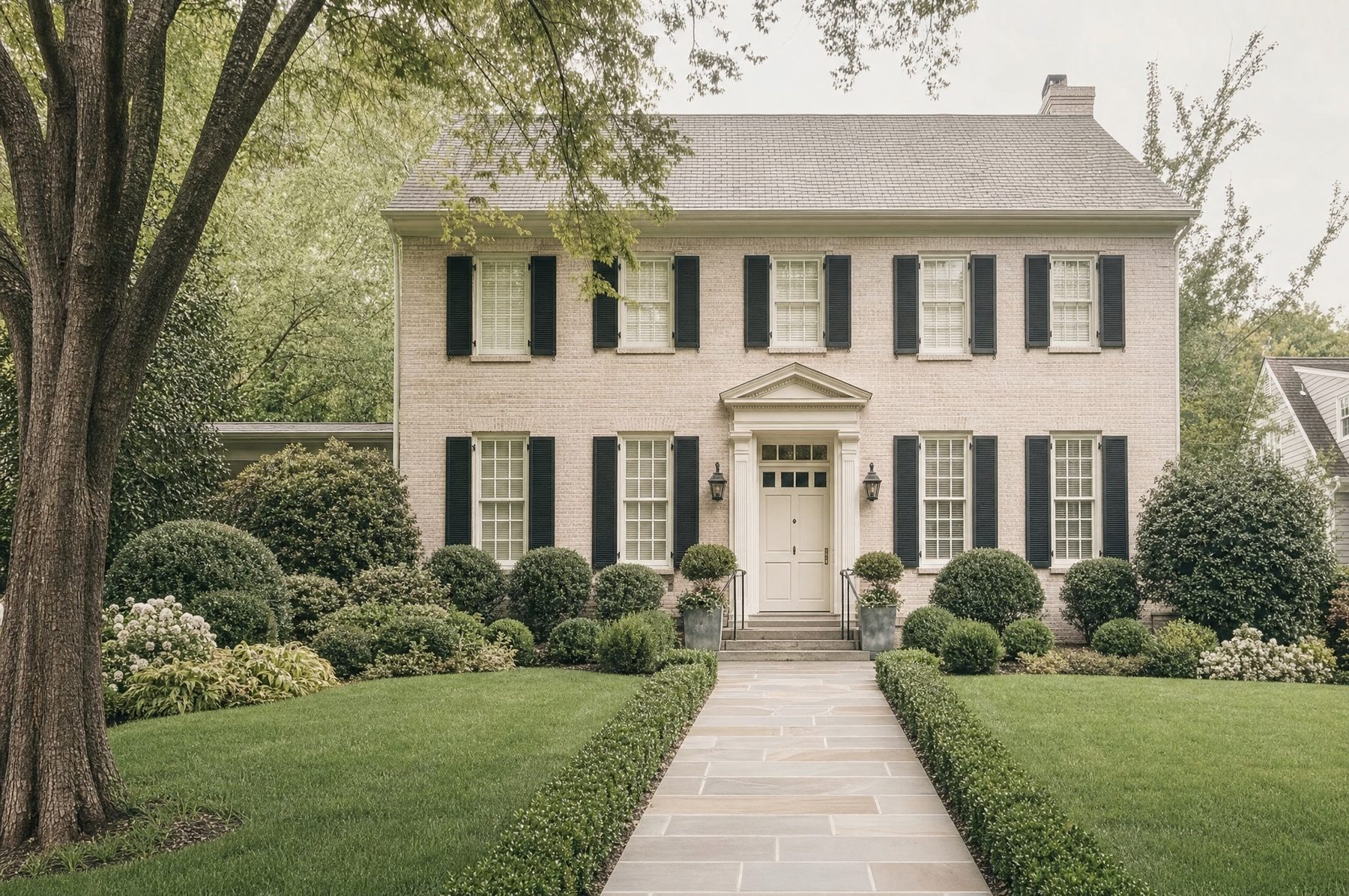 A cream colonial with black shutters and a stone path across the lawn